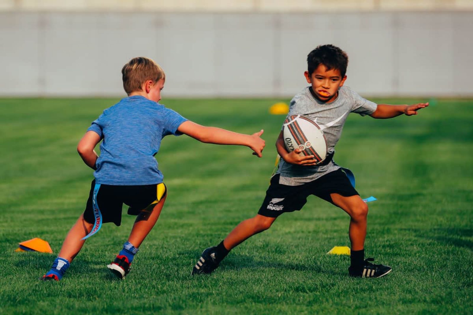 Two students playing flag rugby, one carrying the ball past a defender