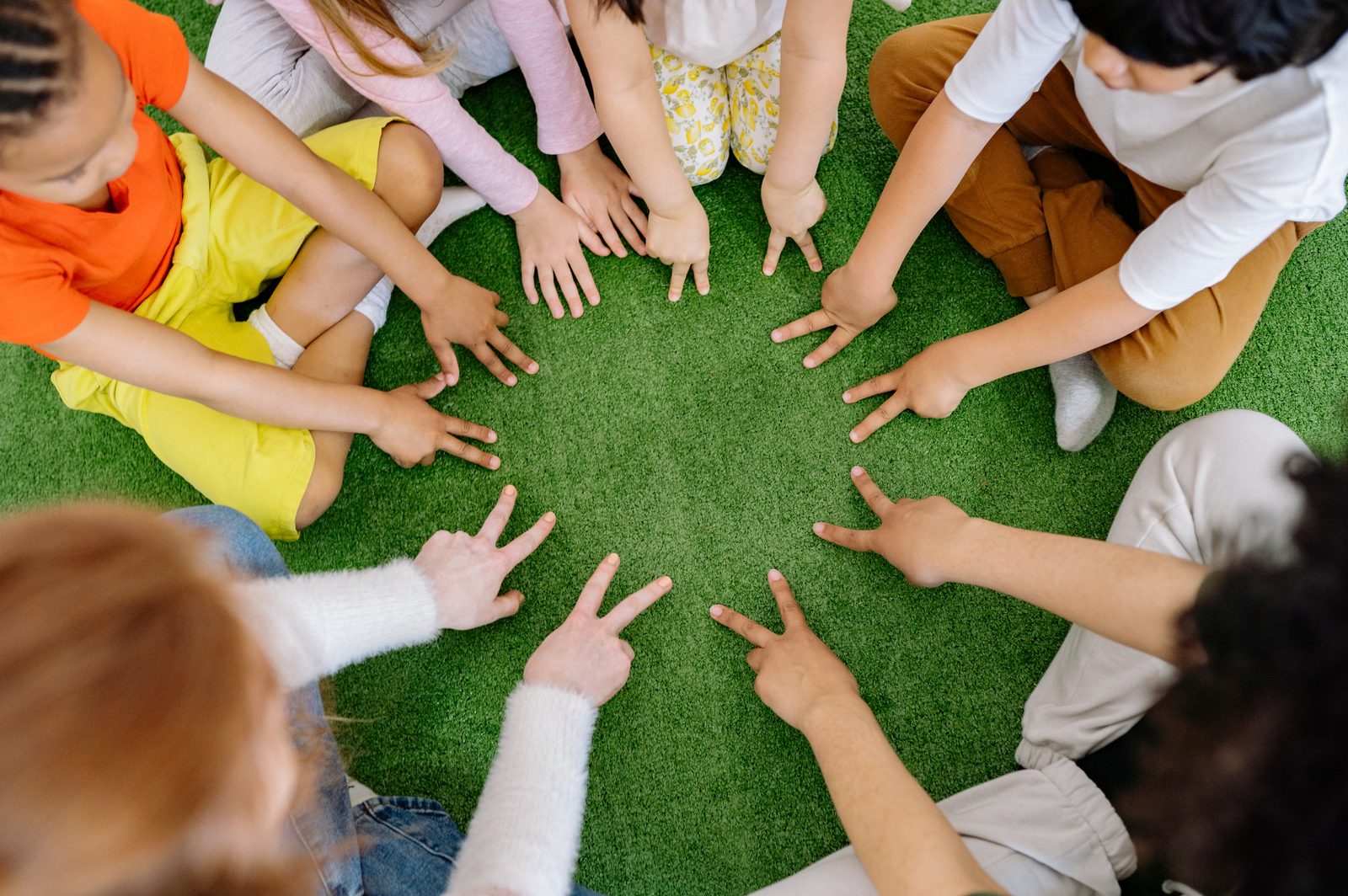 Students sitting in a circle with their hands together in the center