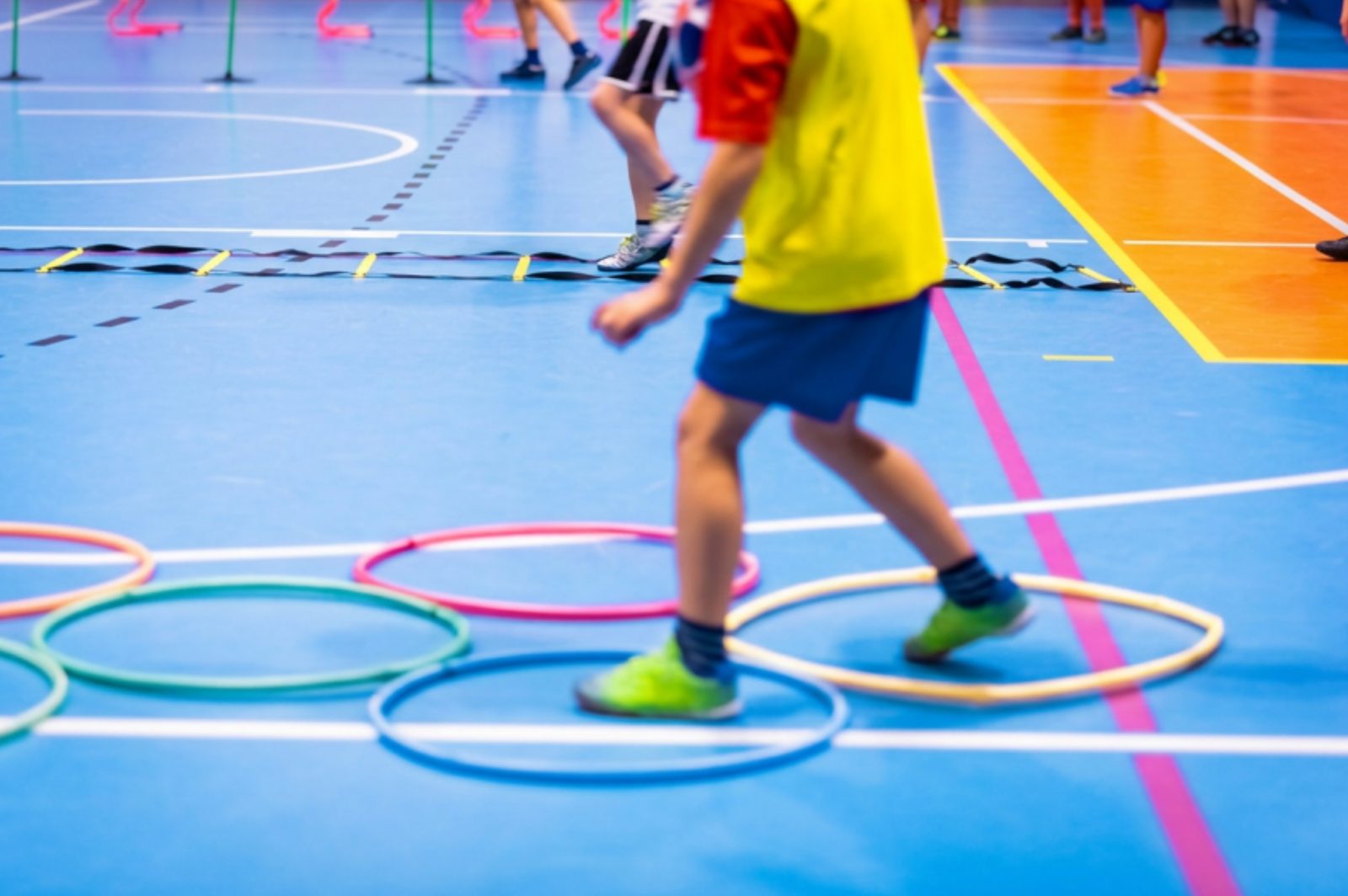 Students moving through an agility drill with cones and hoops from the equipment kit